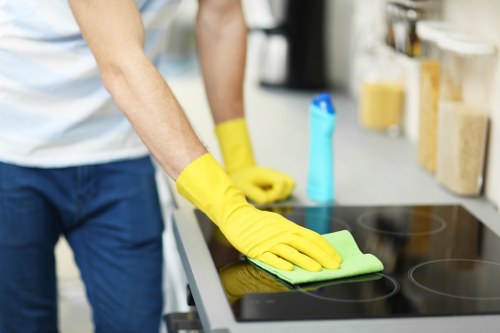 Professional cleaner sanitising desks and shared surfaces in an Acton office