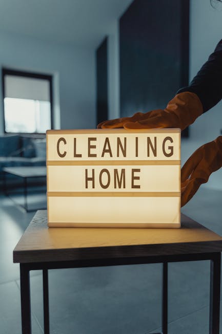A beige wall with a small, light blue wall hook holding a wooden cleaning brush with light brown bristles and a light blue dustpan. The dustpan and brush are positioned vertically on the wall, with th